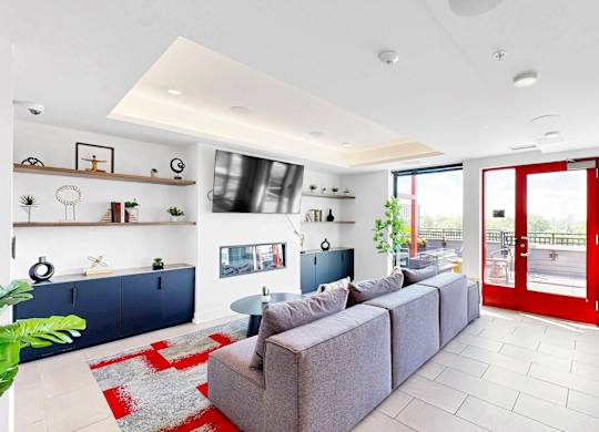 A modern living room with a grey sofa and a red rug.