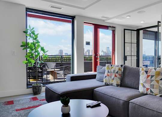 A grey couch with a pillow on it in a room with a view of the city.