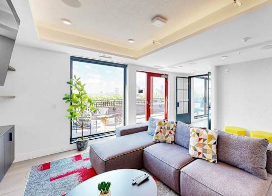 A living room with a grey couch and a glass table.
