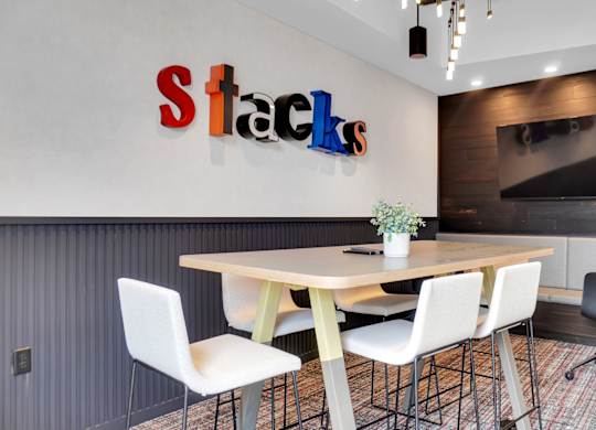 A conference room with a table, chairs, and a sign that says Stacks.