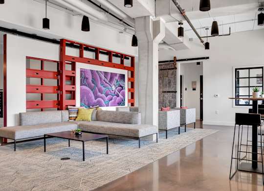 A modern living room with a grey sofa and a large painting on the wall.