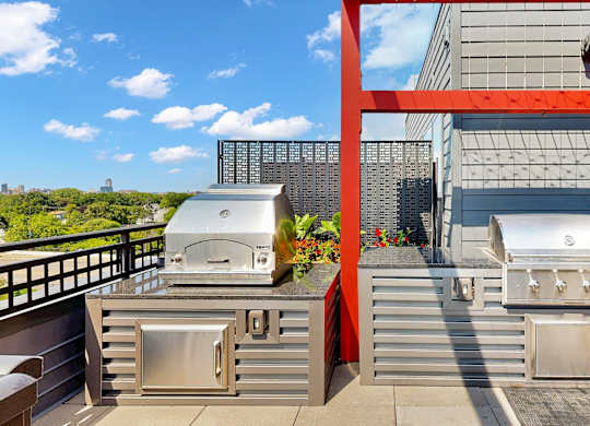 A modern outdoor kitchen with stainless steel appliances and a red frame.