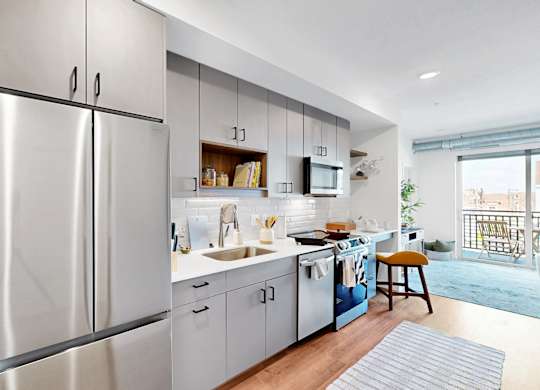 A modern kitchen with stainless steel appliances and a wooden floor.