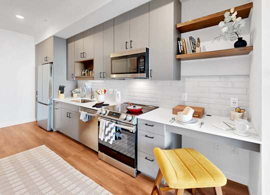 A modern kitchen with a yellow chair and white cabinets.