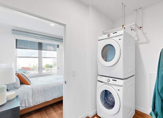 A white washer and dryer stacked on top of each other in a laundry room.