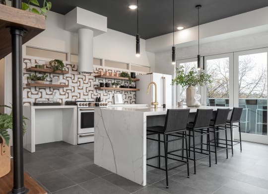 a kitchen with white cabinets and a large island with a white countertop and black chairs