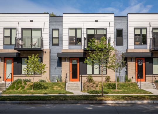 a row of townhomes with white siding and orange doors