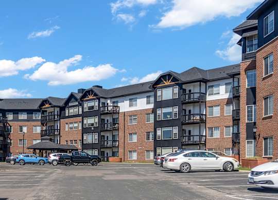 A parking lot in front of a large apartment complex.