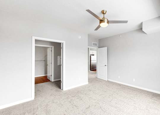 A room with a ceiling fan and carpeted floor.
