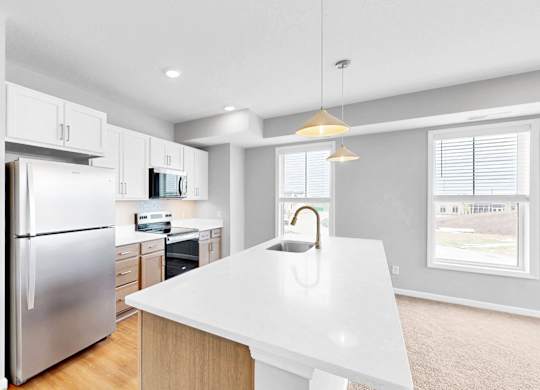 A modern kitchen with a white countertop and stainless steel appliances.