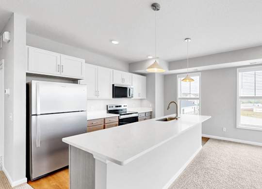 A modern kitchen with a white island and stainless steel appliances.