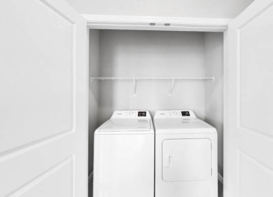Two white washing machines in a white laundry room.