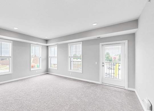 A spacious room with grey carpeting and white walls.