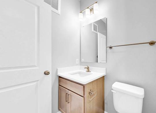 A white bathroom with a toilet, sink, and mirror.