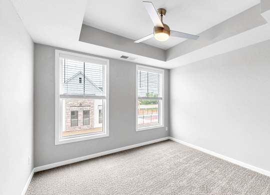 A room with a carpeted floor and a ceiling fan.