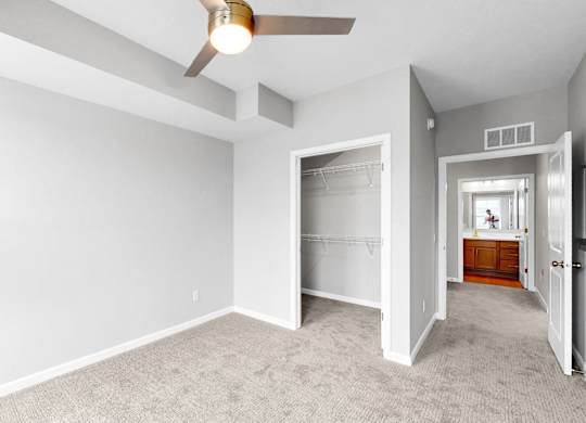 A room with a ceiling fan and carpeted floor.