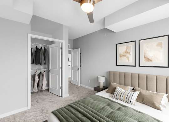 A bedroom with a bed, a ceiling fan, and two framed pictures on the wall.