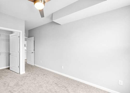 A room with a ceiling fan and a doorway leading to another room.