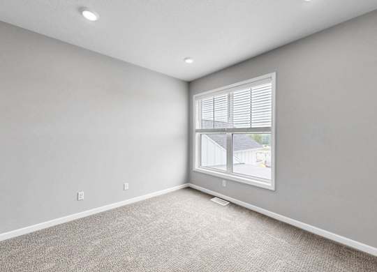A room with a window and a carpeted floor.