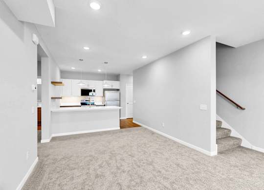 A spacious, empty room with a staircase on the right side.