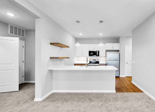A white kitchen with a white island and a white fridge.