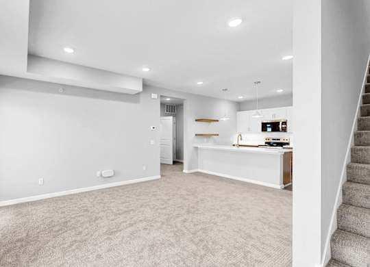 A spacious, empty room with a staircase on the right side.