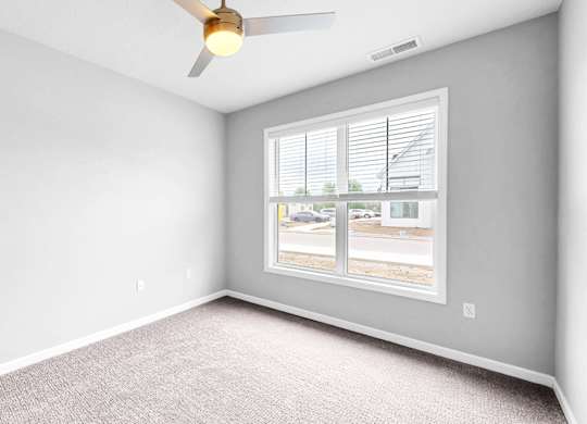A room with a window showing a view of a street with cars and houses.