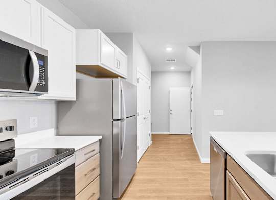 A modern kitchen with stainless steel appliances and wooden floors.