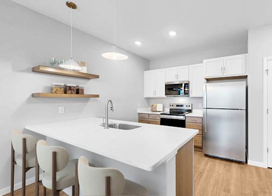A modern kitchen with white countertops and stainless steel appliances.