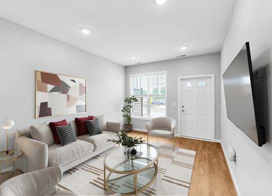 A modern living room with a glass coffee table and a large painting on the wall.