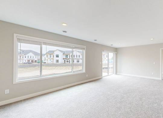 Bright living room with large windows and neutral carpet at Wildwood Lakeville Apartments, Lakeville, MN