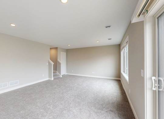 Empty carpeted room with sliding door access at Wildwood Lakeville Apartments, Lakeville, Minnesota