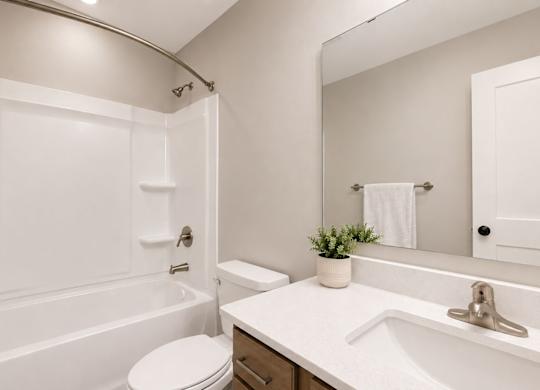 Modern bathroom with white countertop and tub at Wildwood Lakeville Apartments, Lakeville