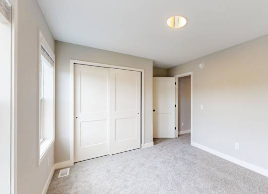 Empty bedroom with walk-in closet and carpet at Wildwood Lakeville Apartments, Lakeville, 55044