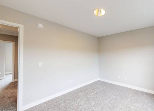 Empty carpeted room with vaulted ceiling at Wildwood Lakeville Apartments, Lakeville, Minnesota