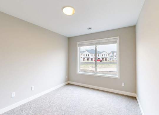 Empty carpeted room with large window at Wildwood Lakeville Apartments, Lakeville, MN