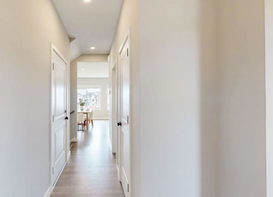 Bright hallway with white doors and wood flooring at Wildwood Lakeville Apartments, Lakeville