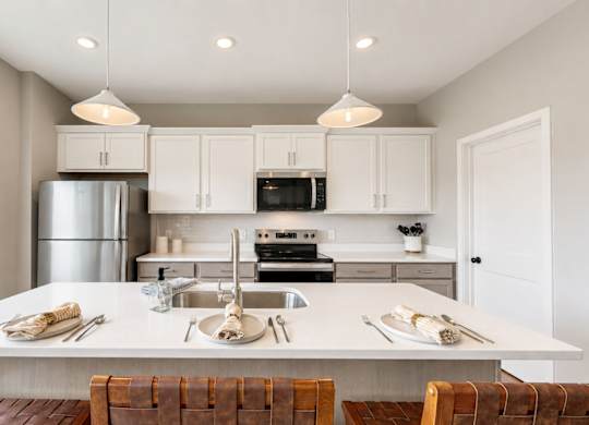 Modern kitchen island with white countertops and seating at Wildwood Lakeville Apartments, Lakeville, Minnesota