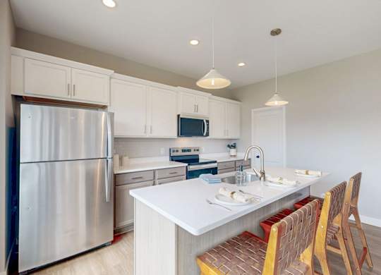 Modern kitchen with white cabinets and island seating at Wildwood Lakeville Apartments, Lakeville