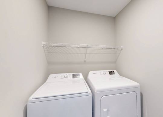 In unit washer and dryer with shelving above at Wildwood Lakeville Apartments, Lakeville, Minnesota