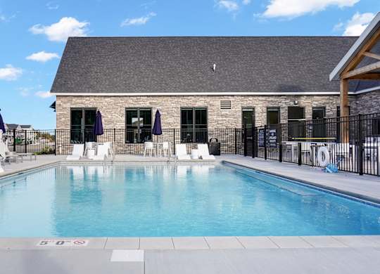 A swimming pool with a black fence and a building in the background.