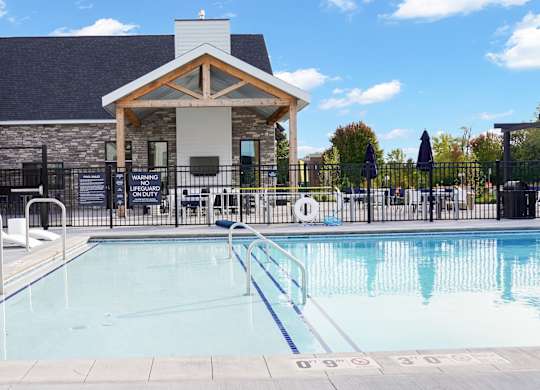 A swimming pool with a diving board and a building in the background.