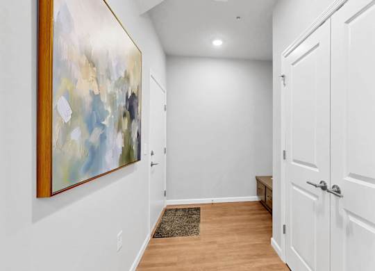 A hallway with a painting on the wall and a door on the right.