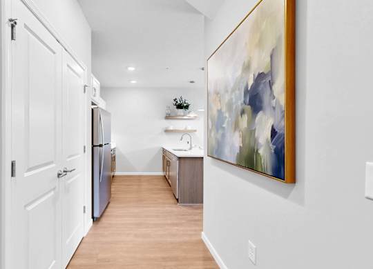 A modern kitchen with white cabinets and a painting on the wall.