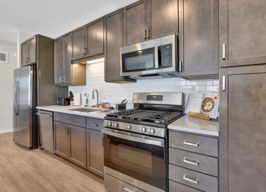 a kitchen with dark wood cabinets and stainless steel appliances