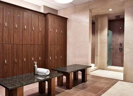 A bathroom with a row of brown lockers and a black table at One West,  New York,10004.