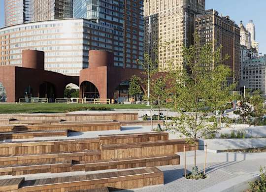 A park with wooden benches and a building in the background at One West,  New York,10004