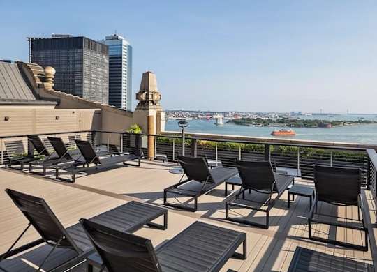 A balcony with black chairs and a view of the city. at One West, New York