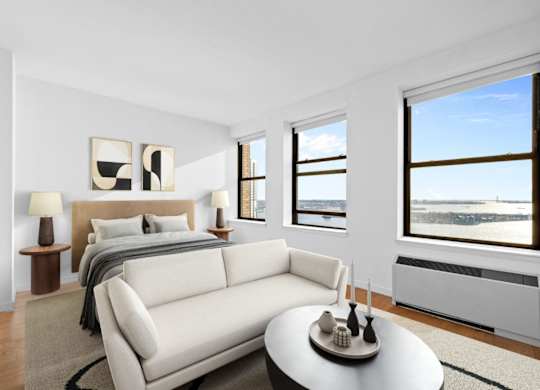 A bedroom with a large bed and a couch. at One West,New York, NY