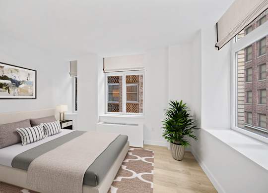 A bedroom with a bed, a potted plant, and a window with a view of a building at Aria, New York, New York